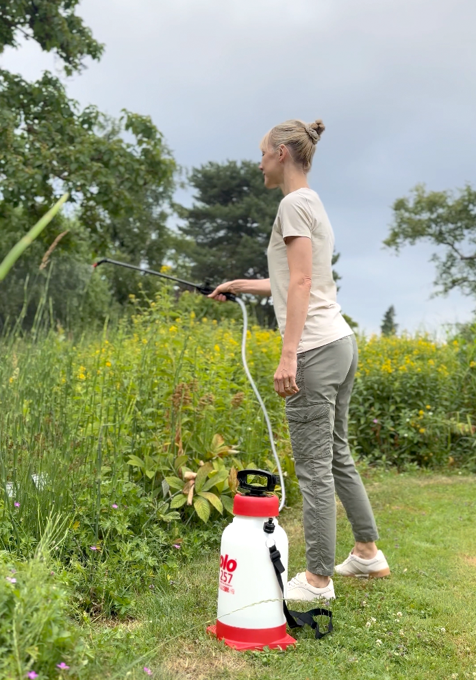 Frau mit SOLO 257 Drucksprüher behandelt hohe Gartenpflanzen mit Pflanzenschutzmittel.